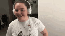 a woman wearing headphones and a white shirt smiles for the camera