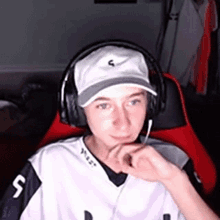 a young boy wearing headphones and a hat is sitting in a chair .