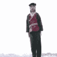 a man is standing in the snow with his arms outstretched and a red shirt on .