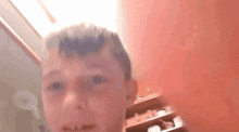 a young boy is making a funny face in front of a red wall