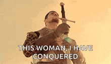 a man in armor is holding a sword in his mouth .