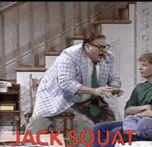a man in a plaid shirt is squatting in front of a boy in a green shirt who is sitting on a couch