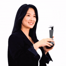 a woman in a black suit holds a trophy that says hm