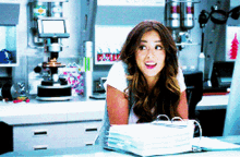a woman is sitting at a desk with a stack of binders