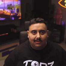 a man wearing a black shirt that says topz