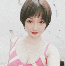 a woman in a pink and white striped tank top looks at the camera