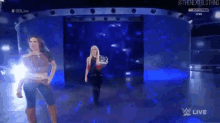 a couple of women are standing on a stage in a dark room .