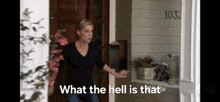 a woman is standing in front of a door with the words what the hell is that written on it .