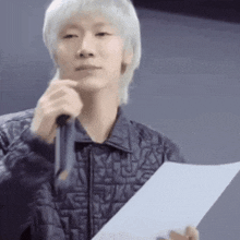 a man is holding a piece of paper and a microphone .