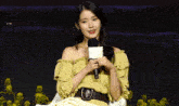 a woman in a yellow dress holds a microphone
