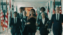 a group of women are walking down a hallway with flags in the background