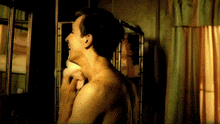 a man without a shirt is shaving his neck in front of a mirror