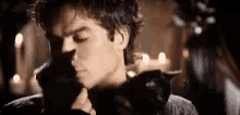 a man is holding a black cat in his arms while a woman looks on .
