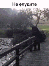 a man in a suit is standing on a bridge over a body of water .