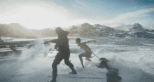 a man and a woman are playing in the snow with mountains in the background