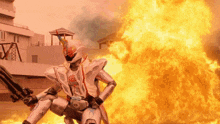 a man in a robot costume is standing in front of a large fire