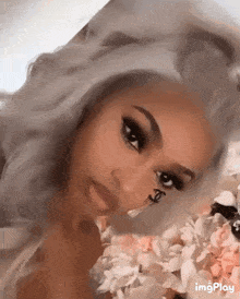 a close up of a woman 's face with flowers in the background and a spider on her face .