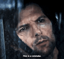 a man with a beard is looking out a window and says this is a mistake .