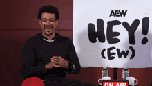 a man is sitting in front of a sign that says hey