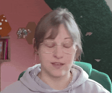a woman wearing glasses and a gray hoodie looks at the camera
