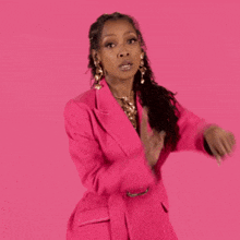 a woman is wearing a pink jacket and earrings .