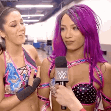 a woman with purple hair is being interviewed by a wrestler