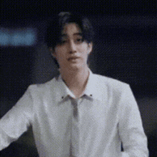 a young man in a white shirt and tie is standing in front of a black background .