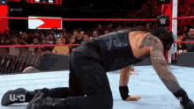 roman reigns is kneeling down in a wrestling ring during a match