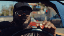 a man wearing sunglasses is driving a car