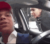 a man in a red hat is sitting in a car with a woman behind him