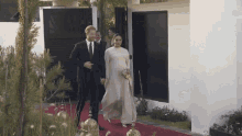 a man and woman are walking on a red carpet .