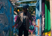 a man standing in front of a colorful wall with graffiti on it