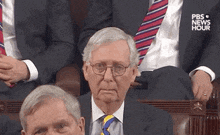 a man in a suit and tie is sitting in a parliament .