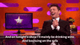 a man in a suit and tie is sitting in front of a screen that says ' and on tonight '