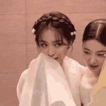 two women are standing next to each other and one is covering her face with a cloth