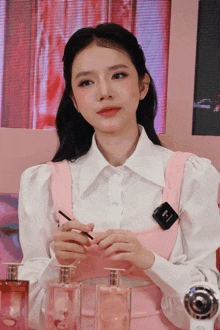 a woman in a pink dress is holding a brush and a bottle of perfume