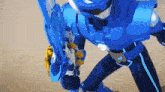 a blue robot is holding a gun and a sword in his hands .