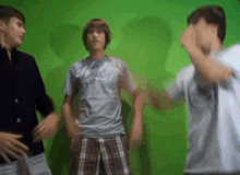 a group of young men are dancing in front of a green screen .