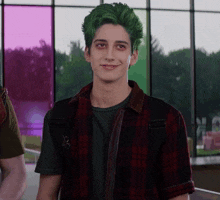a young man with green hair is smiling in front of a window
