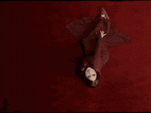 a woman is looking through a hole in a red wall
