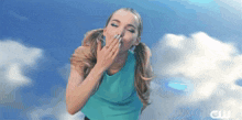 a woman in a blue top is blowing a kiss in the air