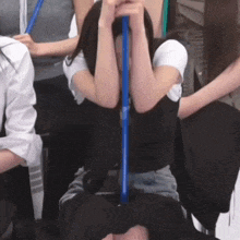 a woman is covering her face with a blue straw