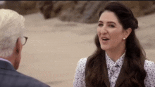 a man and a woman are sitting on a beach talking to each other .
