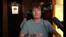 a young man wearing headphones and a blue shirt is standing in front of a microphone .