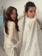 two women in white dresses are posing for a picture together
