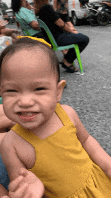 a little girl in a yellow dress is smiling and looking at the camera