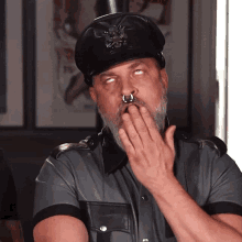 a man with a nose ring is wearing a leather hat