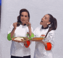 two women are holding plates of food and one has a shirt that says fox on it