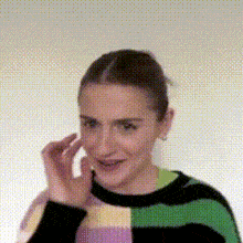 a woman in a striped sweater is smiling and touching her face