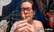 a woman wearing glasses is lighting a cigarette with a match .
